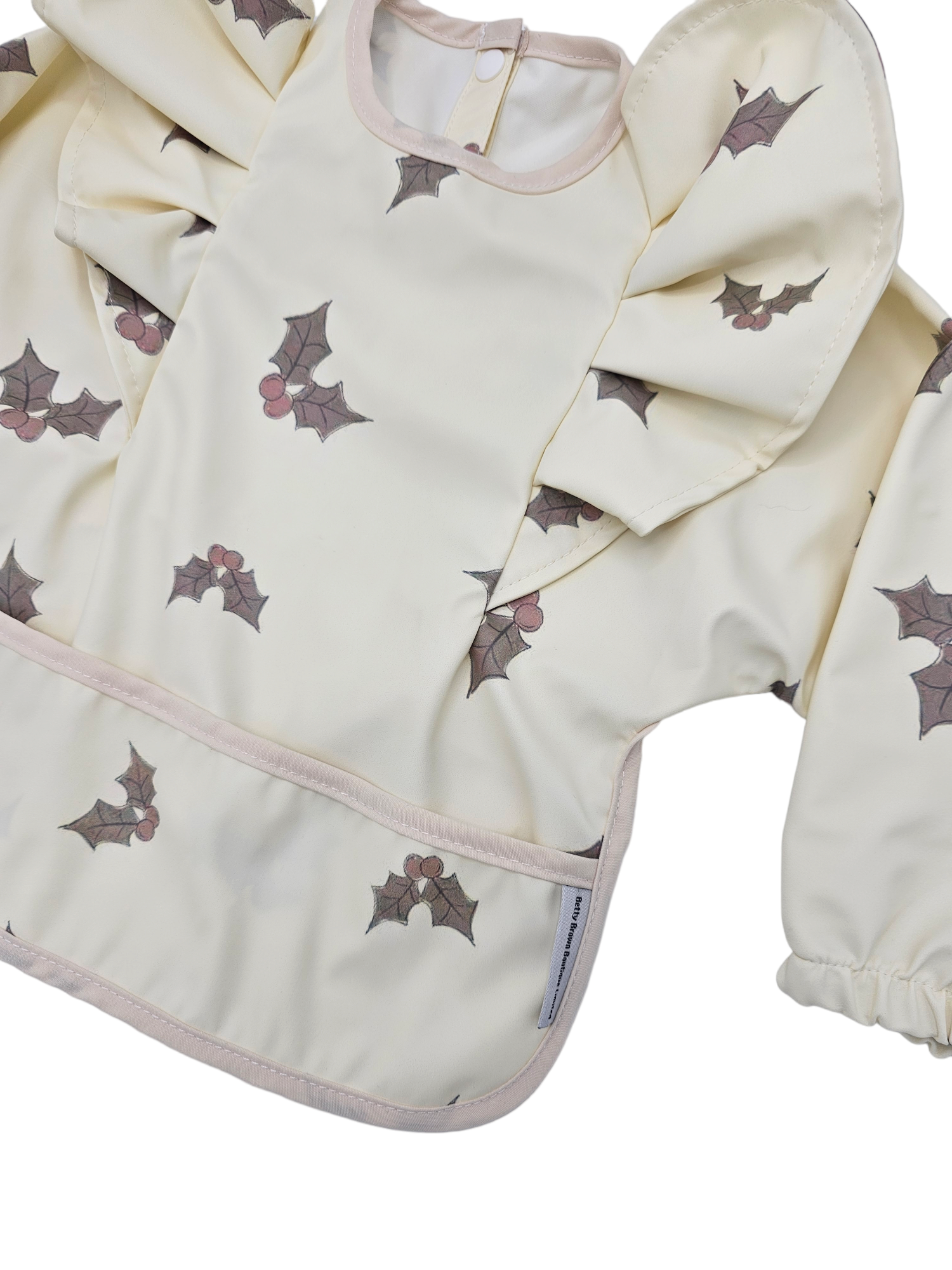 Cream Holly Print Frill Detail Waterproof Bib with Sleeves - Limited Edition Christmas Collection - Betty Brown Boutique Ltd