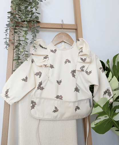 Cream Holly Print Frill Detail Waterproof Bib with Sleeves - Limited Edition Christmas Collection - Betty Brown Boutique Ltd